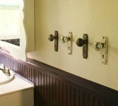 an old door knobs to hang towels on the wall next to a bathroom sink