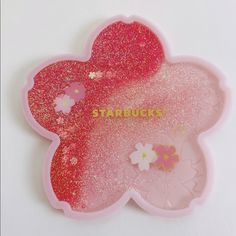 a pink and gold glittered flower shaped tray with the words starbucks written on it