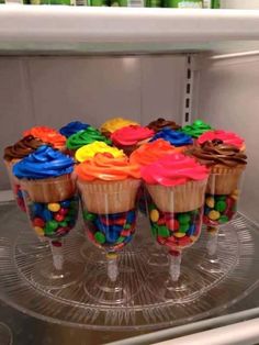 cupcakes with colorful icing on them sitting on a glass plate in front of a microwave