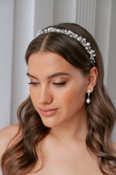 a woman wearing a bridal headpiece with pearls and crystals on the top of her hair