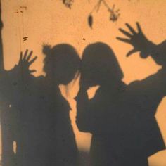 shadow of two people standing next to each other with their hands in front of them