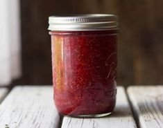 a jar filled with red sauce sitting on top of a wooden table