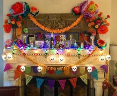 a decorated mantle with skulls, flowers and candles on it in front of a fire place