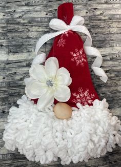 a red bag with white flowers on top of a pile of knitted wools