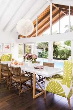 a dining room table with green chairs next to a swimming pool