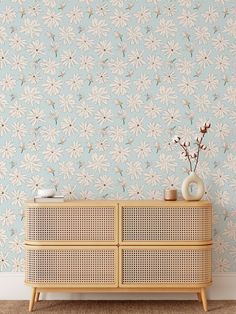 a wooden dresser with two vases on top of it next to a wall paper