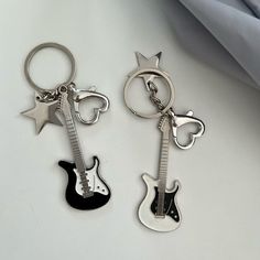 two keychains with guitars and stars on them, one is black and the other is silver