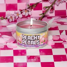 a pink candle sitting on top of a checkered tablecloth with flowers in the background