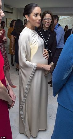 a woman in a white dress standing next to other women