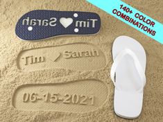 two pairs of flip flops are laying on the sand next to a pair of personalized slippers