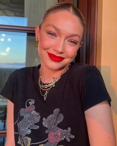 a woman with red lipstick is smiling at the camera while wearing a mickey mouse t - shirt