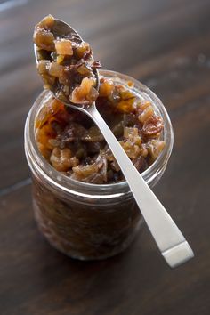 a spoon with some food in it sitting on a table next to a glass jar