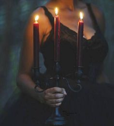 a woman holding three candles in her hands