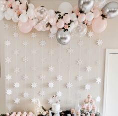 a table topped with cakes and desserts next to a wall covered in snowflakes