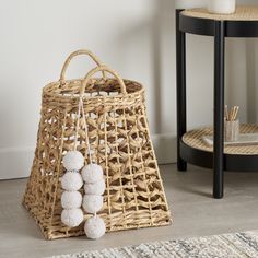 a wicker basket with pom - poms on the floor next to it