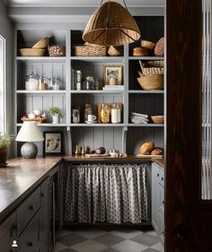 a kitchen with lots of shelves and baskets on top of the cabinets, next to a window