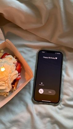 a cell phone sitting on top of a table next to a box filled with food