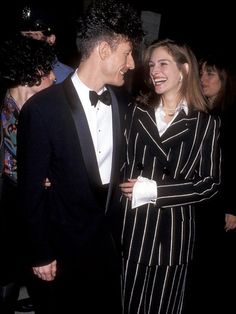 two people standing next to each other in formal wear and tuxedos at an event