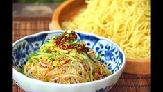 two bowls filled with noodles and vegetables on top of a table