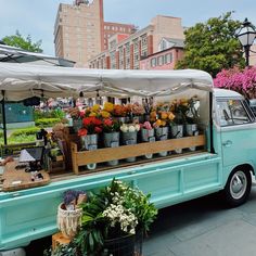 an old blue truck is selling flowers and plants