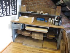 a desk with many boxes and papers on it in front of a red brick wall