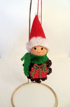 a christmas ornament hanging from a ring on a white surface with a red hat and green scarf