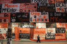 a person walking in front of a wall covered with orange and black signs