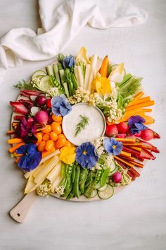 a platter filled with different types of vegetables and dip surrounded by white napkins