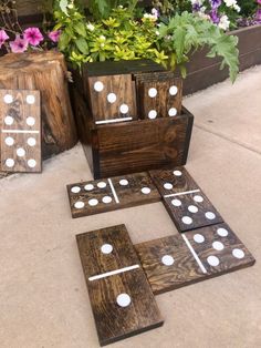 four wooden blocks with white dots on them sitting in front of some potted plants