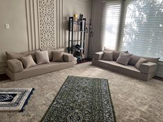 a living room with couches and rugs in front of the window, next to a bookcase