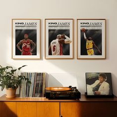 three framed sports photos hang on the wall above a record player's desk and records