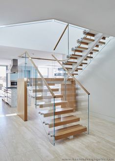 a staircase with glass railing and wooden handrails in a modern style home setting