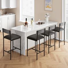 a kitchen with white counter tops and black chairs