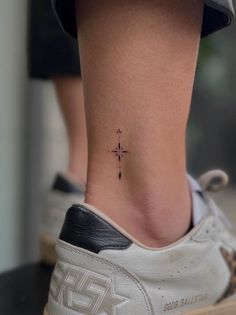 a woman's foot with a small cross tattoo on the side of her ankle