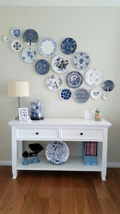 a white table topped with lots of blue and white plates on it's wall