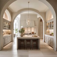 an archway leads into a large kitchen with white cabinets and counter tops, along with bar stools