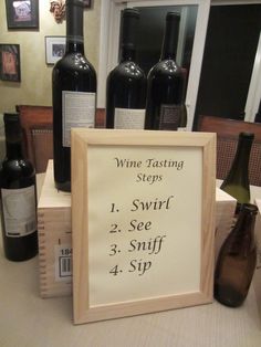 a wine tasting sign sitting on top of a table next to several bottles of wine