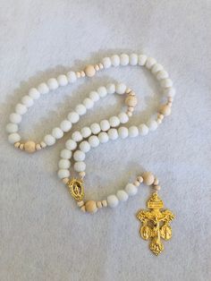 "This soft, beautiful rosary makes the perfect gift for any occasion. Carefully crafted with highest quality materials. The Hail Mary beads are made of 100% sheep's wool felt balls and the Our Father beads are natural wood. The high quality gold toned Crucifix and Centerpiece are absolutely beautifully detailed. This unique crucifix is called a Triple Threat Crucifix because it combines 3 of the most powerful sacramentals of the Church into one piece! There is an indulgence granted by Pope Saint Pius X each time you kiss this crucifix. Die cast for exceptional detail.  Hail Mary Wool Beads: 1 cm diameter Our Father Wood Beads: 12 mm diameter Small Wood Spacer Beads: 6 mm diameter Crucifix: 2 1/8\" Total Length when laid flat: approximately 18 inches" White Spiritual Rosary Bracelet With 8mm Beads, Spiritual White Rosary Bracelet With Round Beads, Spiritual Rosary With 8mm Beads For Blessing, Spiritual Beaded Rosary For Blessing, White Spiritual Jewelry With Wooden Beads, Spiritual White Jewelry With Wooden Beads, White Rosary With Wooden Beads As Gift, White Wooden Beads Rosary As Gift, White Rosary Bracelet For First Communion