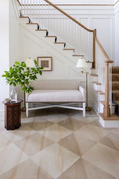 a living room with a couch, table and stair case in front of the stairs