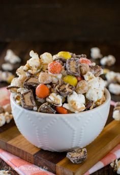 a white bowl filled with candy corn and marshmallows on top of a wooden cutting board