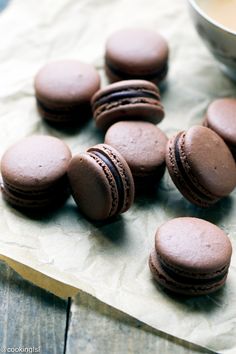 chocolate macaroons and a cup of coffee on a wooden table with parchment paper