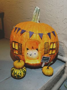 a pumpkin shaped like a house with a cat inside