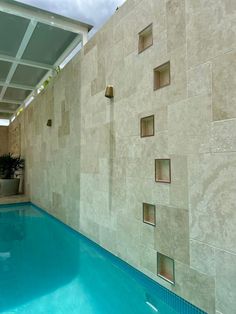 an indoor swimming pool with tiled walls and blue water in the foreground, under a skylight