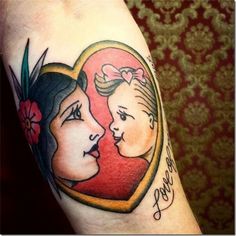 a woman's arm with a heart shaped tattoo on it and an image of two women