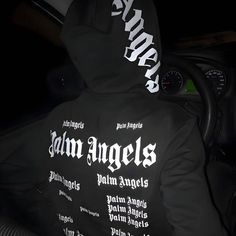 a person in a car wearing a black hoodie with white writing on the back