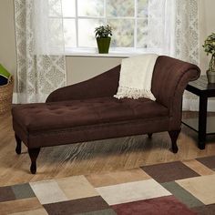 a brown chaise lounger sitting on top of a hard wood floor next to a window