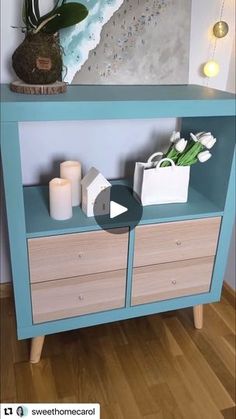 a blue shelf with flowers and candles on it in front of a painting that is hanging on the wall