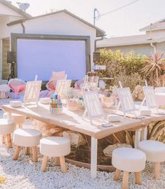 an outdoor movie screen is set up in front of a backyard with white stools