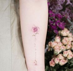 a woman's arm with a pink rose tattoo on the left side of her forearm