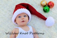 a baby wearing a santa hat laying on top of a white rug next to ornaments